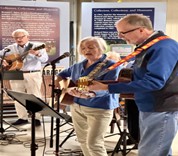 Acadia Senior College musicians play guitar and sing while standing at microphones.
