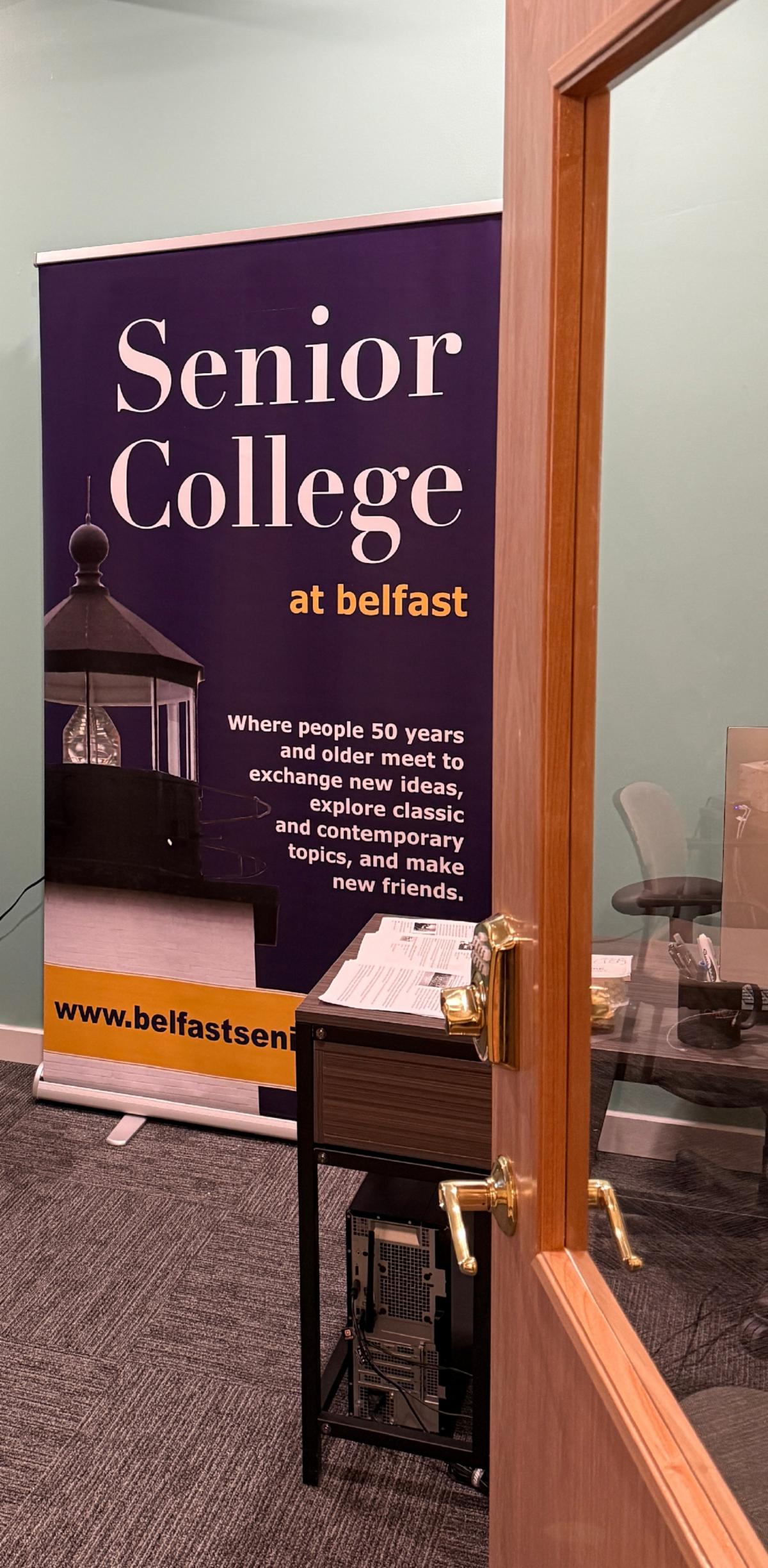 An open door leads to the Senior College at Belfast banner to greet people entering the classroom.
