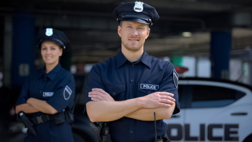 Kind police officers smiling standing near police station_ ready to help_ order