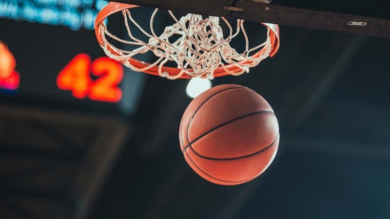 A basketball goes through the hope during a game.
