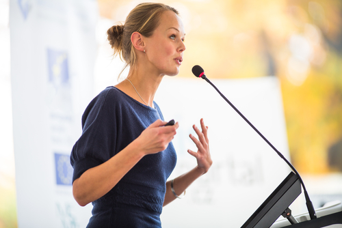 Pretty_ young business woman giving a presentation in a conference meeting setting  shallow DOF  color toned image 