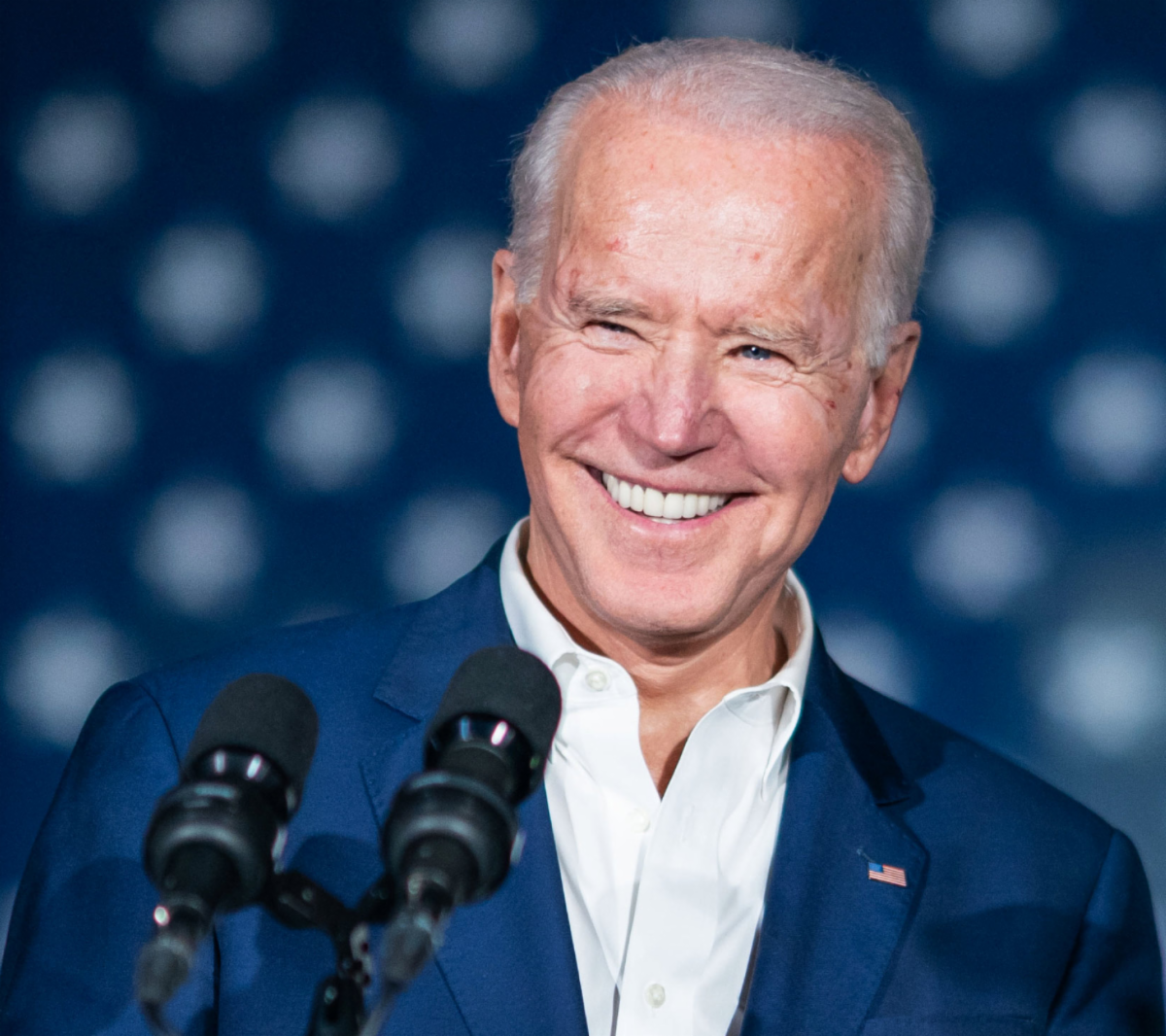President Joseph R. Biden smiling with US Flag behind.