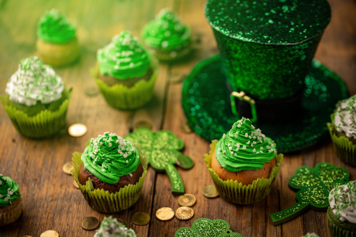 St. Patrick's Day celebration, hat with green glitter surrounded by cupcakes with green frosting. 