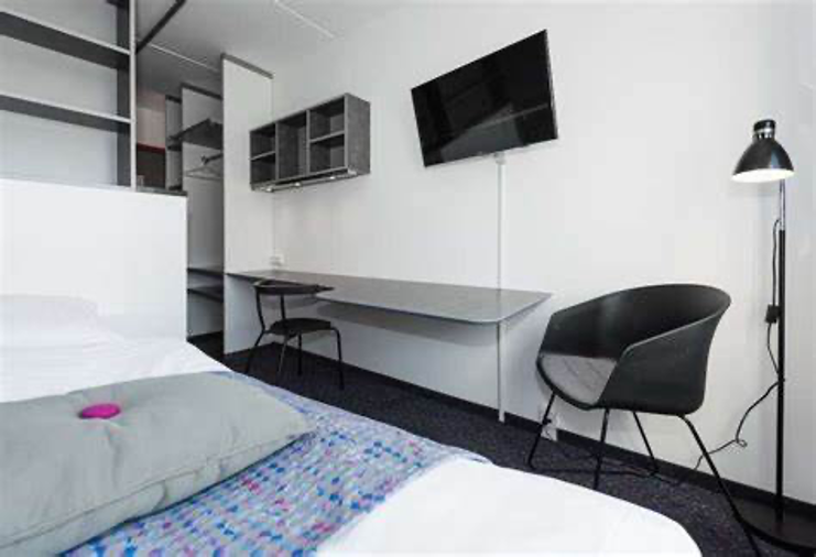 [Image: An inside view of D’Arcee’s hotel room]. 