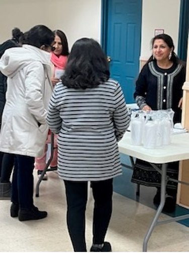 [Image: Ruchika Lalwani sharing information at a resource table].