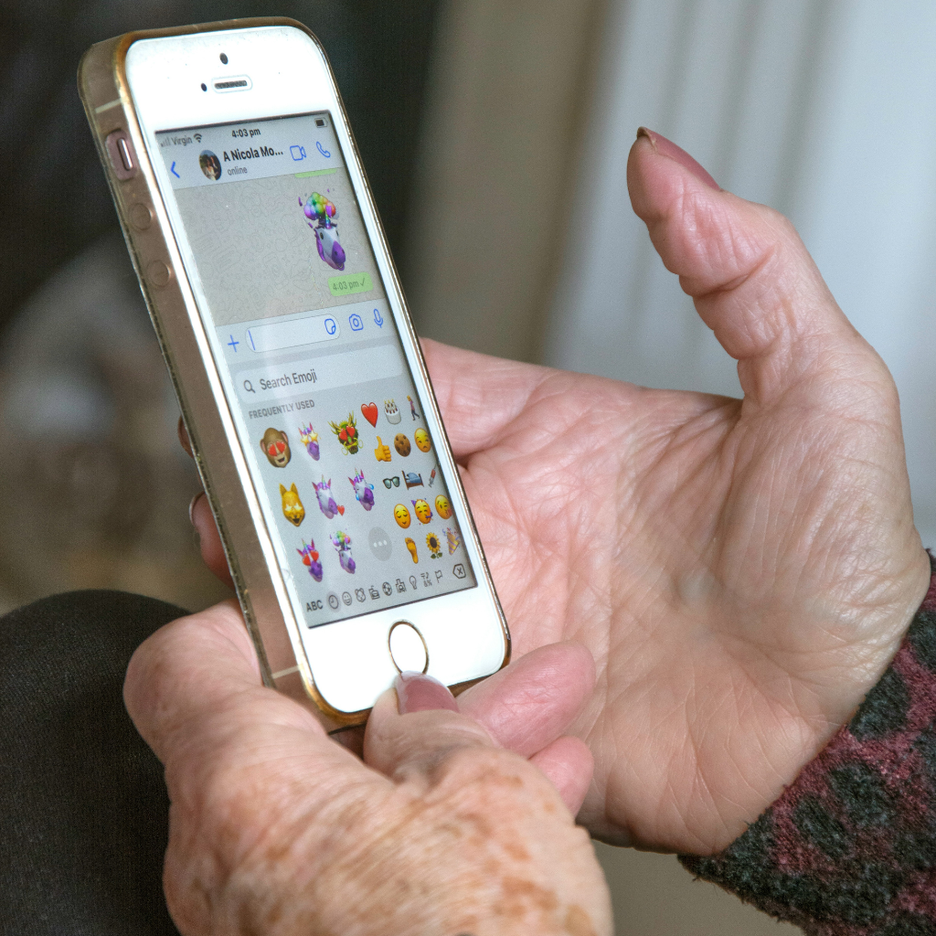 A closeup of hands holding a smartphone and sending an emoji over a text message 