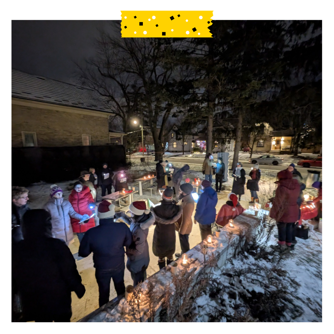 A group of people outside in the dark, holding lights and choir sheets.