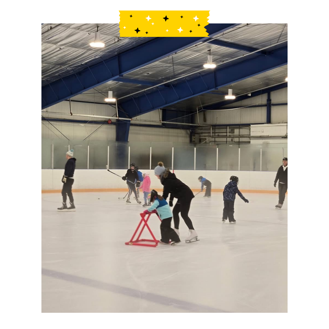 People on a skating rink and skating with a skating aid and others skating around.