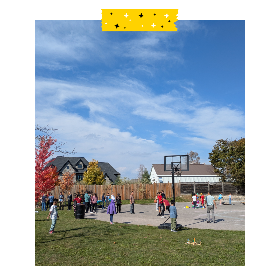 People playing outdoors on the grass and basketball court. Blue sky with some clouds in the background.