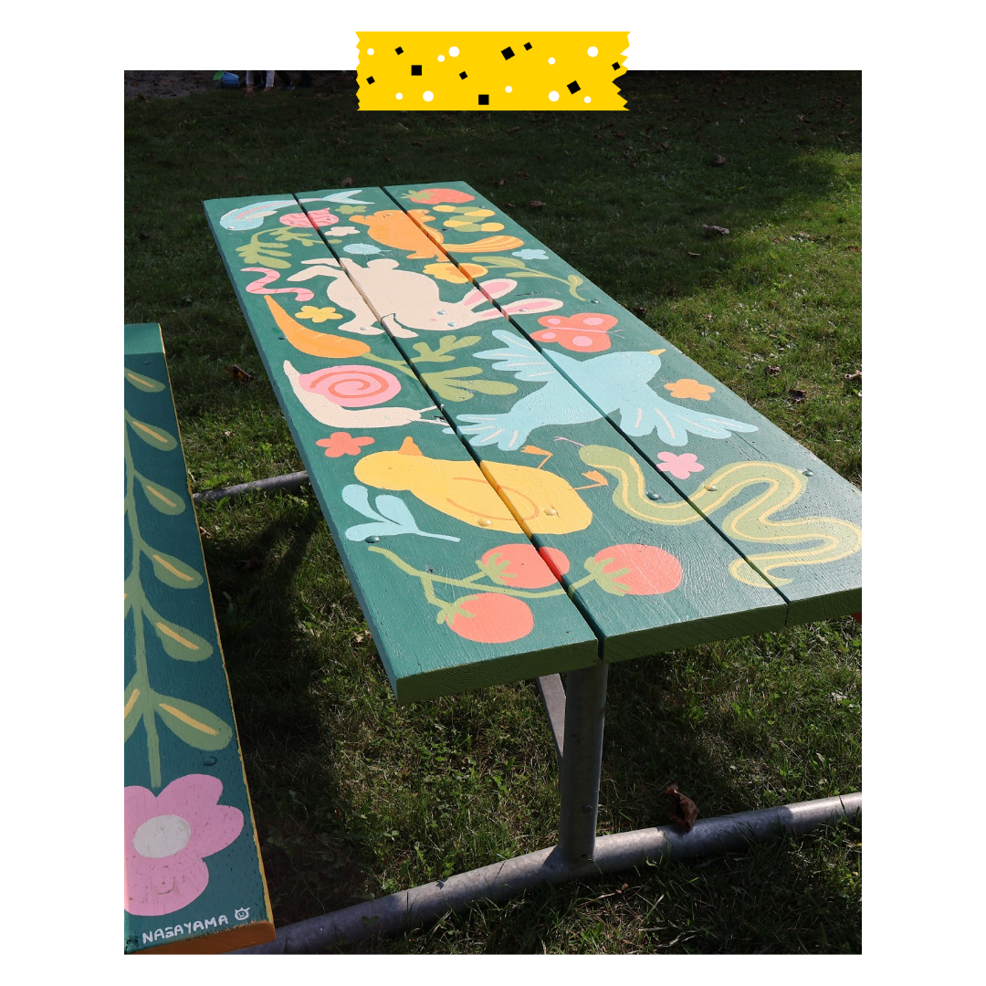 Green picnic table with animals and plants on it.