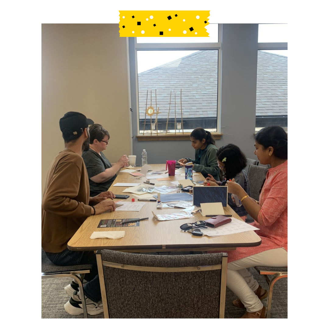 People sitting at a table doing a craft.