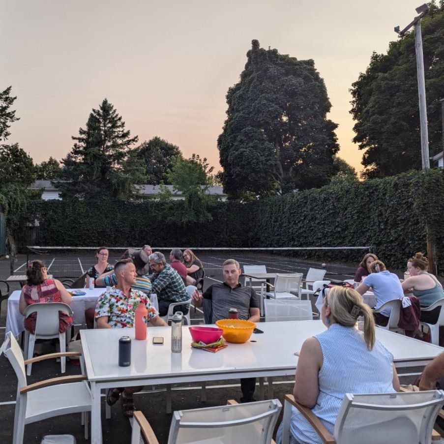 People sitting at tables in an outdoor tennis court