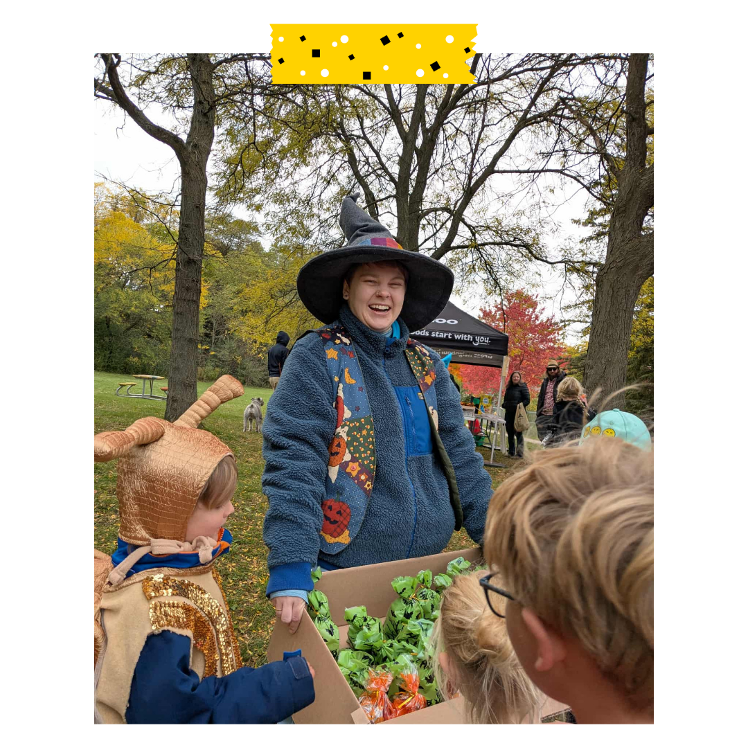A person holding Halloween candy bags with kids taking some.