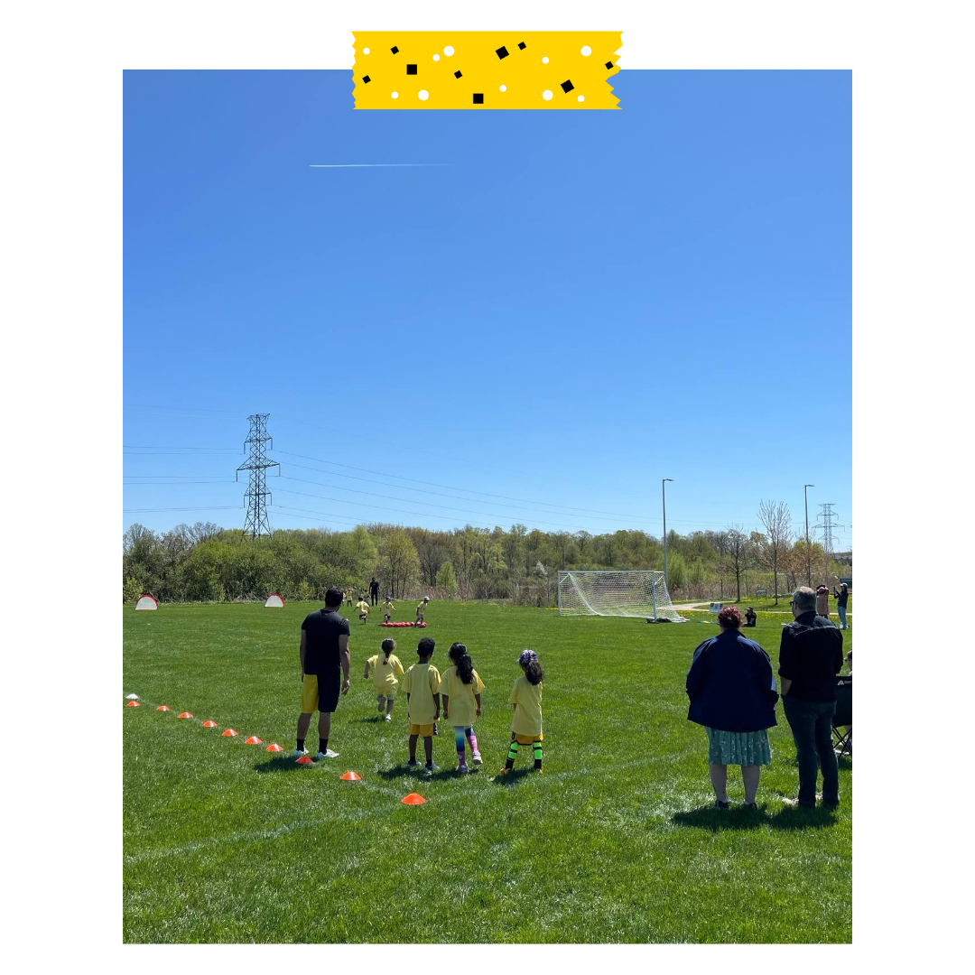 People outside on a soccer field with soccer balls and in soccer jerseys.