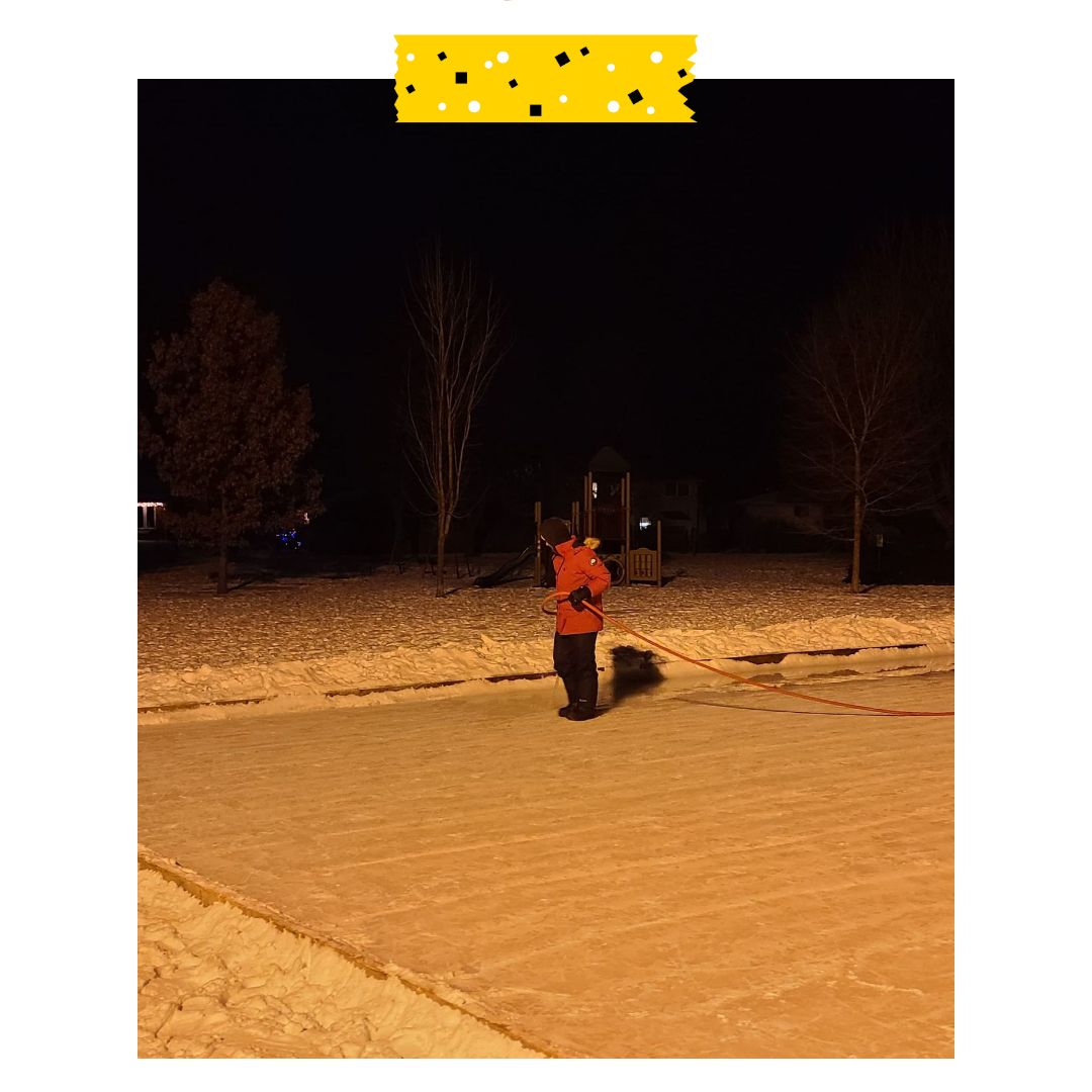 Someone standing on the outdoor rink with a hose and a big coat at night.