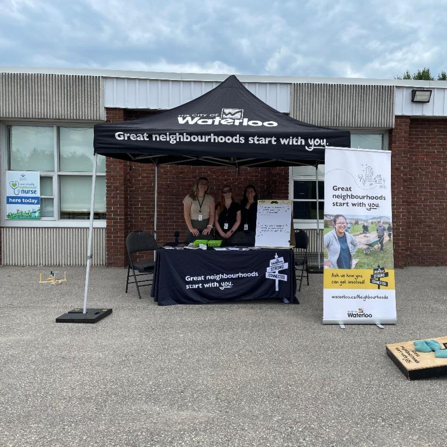 City of Waterloo staff in a booth with tent that reads, great neighbourhoods start with you.