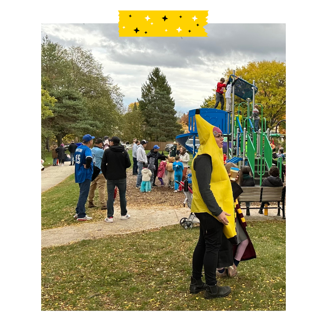 People standing outside in Halloween costumes in a park.