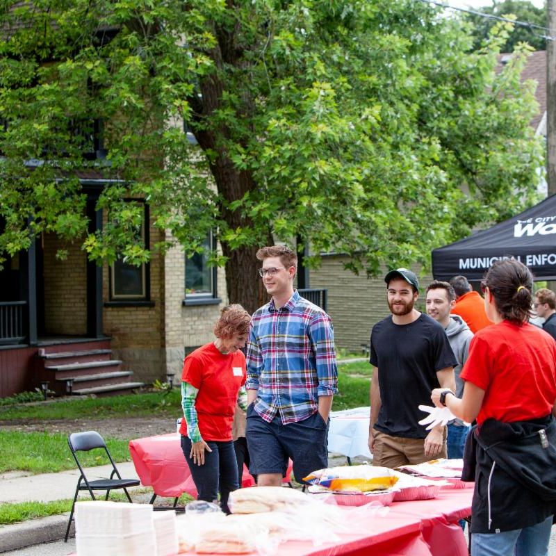 People walking at an event, table and tent in background. 