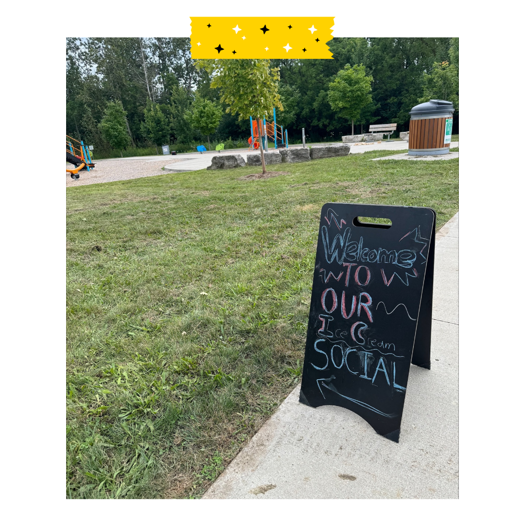 Chalk board sign that says welcome to the ice cream social, sign is in a park