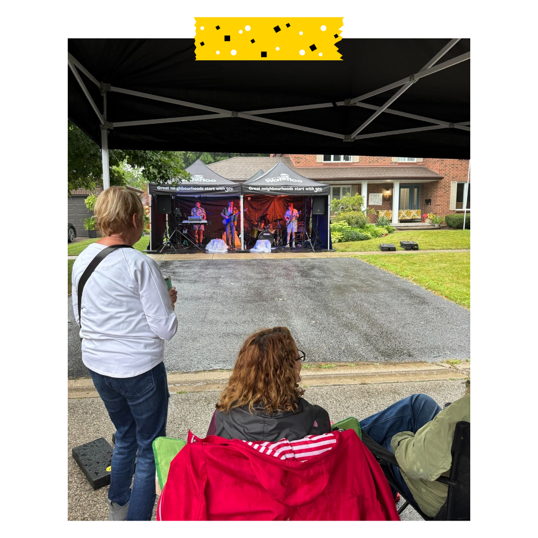 A band playing music under a tent outside and people watching.