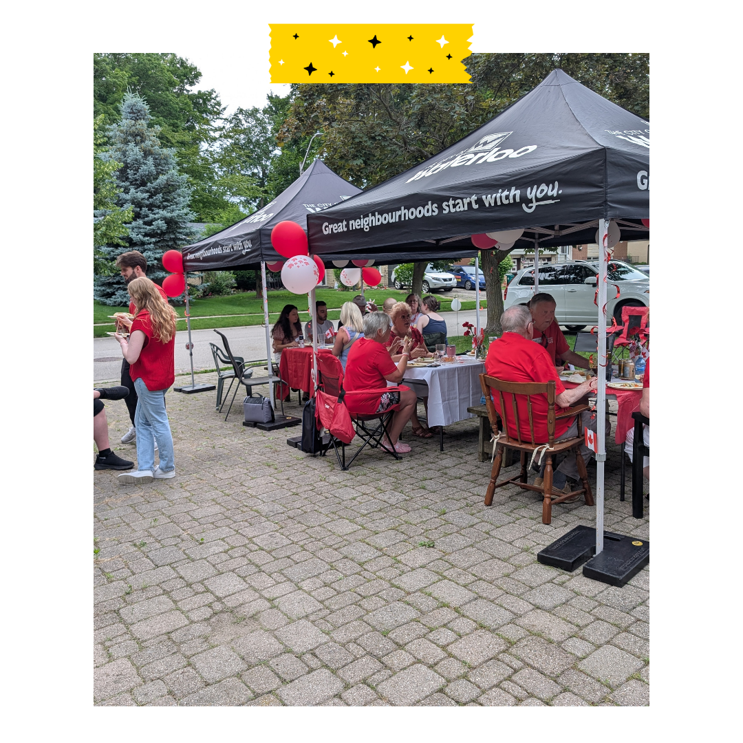 People sitting under tents on a driveway in red shirts for Canada day.