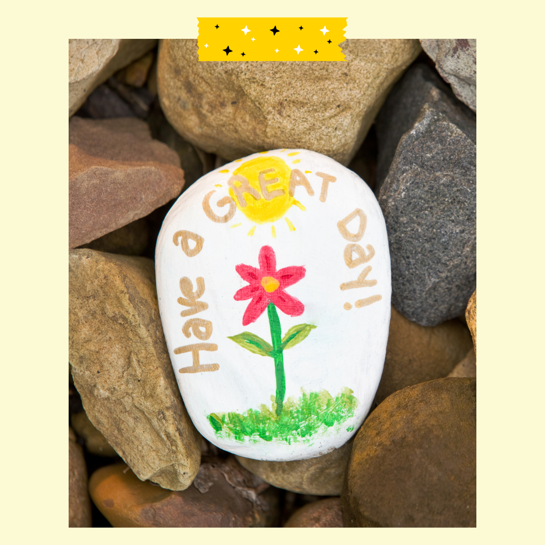 A rock painted with a flower and text that reads have a great day