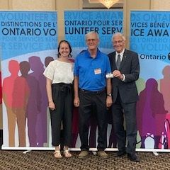 Photo of 3 people standing together at a awards banquet