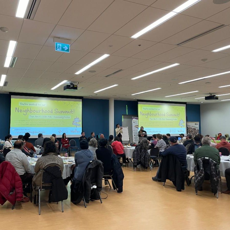 Group of people in room looking at presentation that says Neighbourhood Summit
