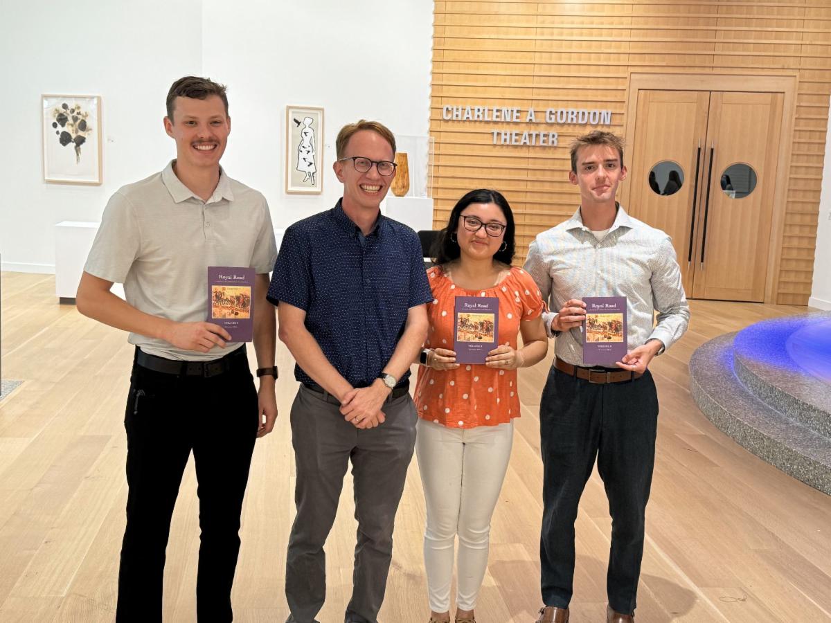 the three student authors are picture with Dr. Steven Mollman holding copies of Royal Road