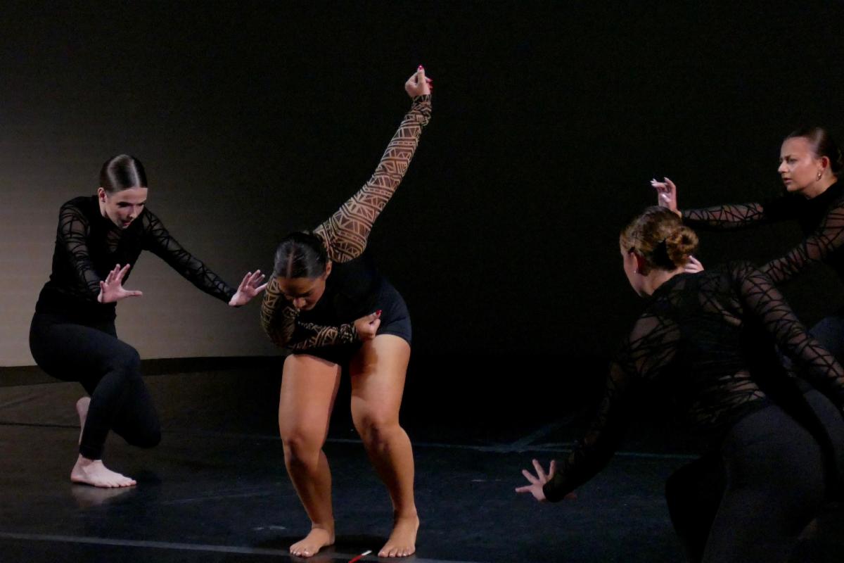 Four dancers dressed in black in a contemporary dance