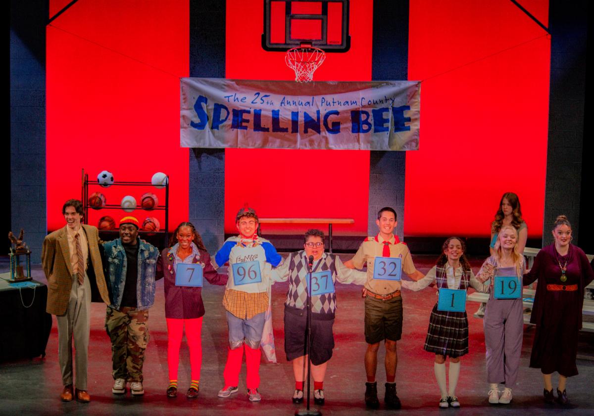 Photo of spelling bee participants with sign in the background