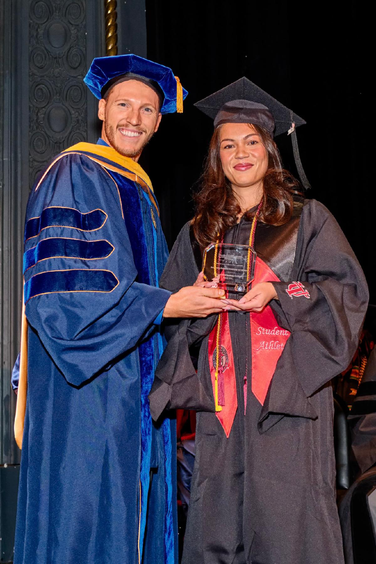 Dr. Stephen Kromka handing a student an award in academic regalia