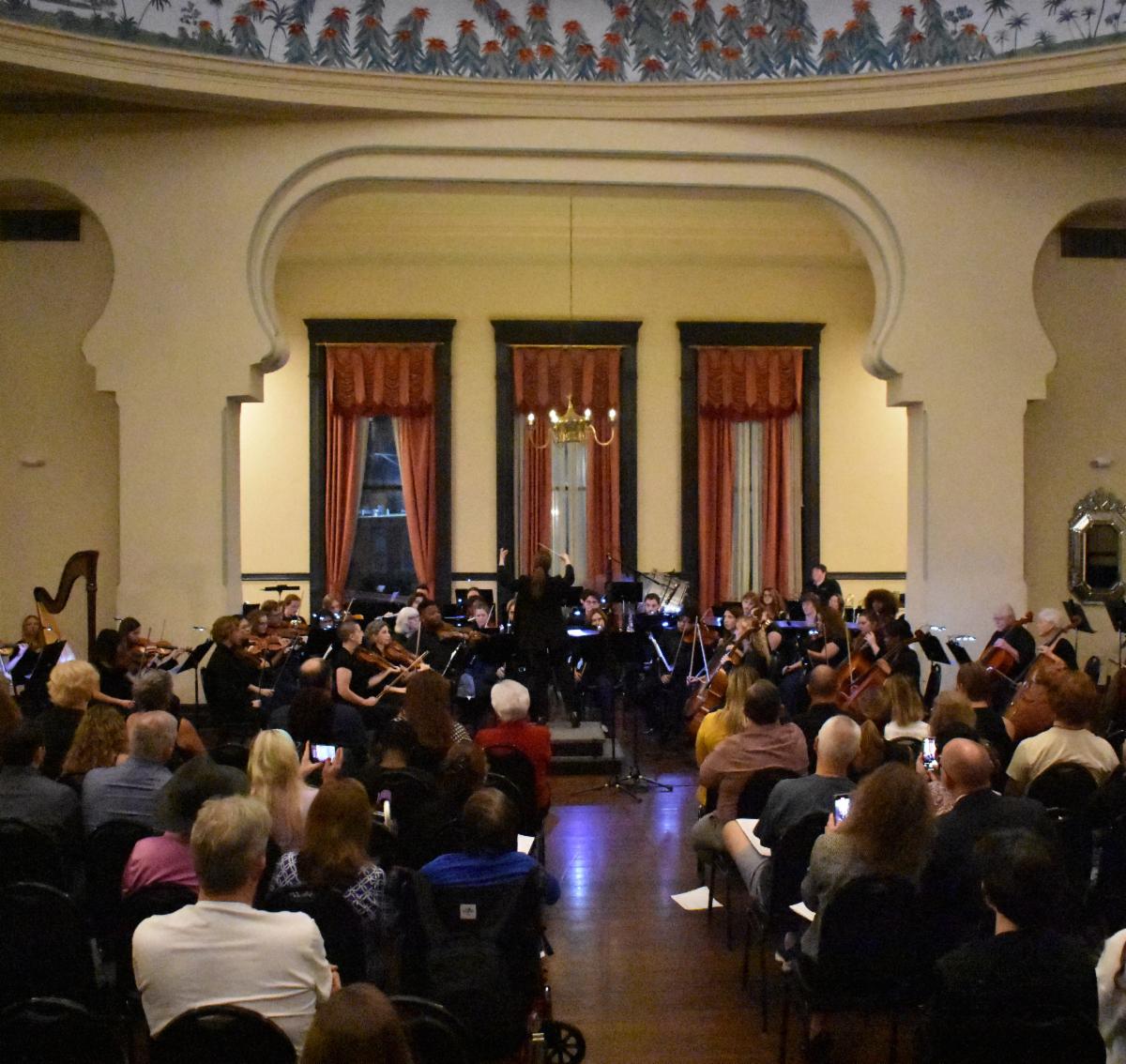 Megan Maddelano conducting the orchestra in Fletcher Hall