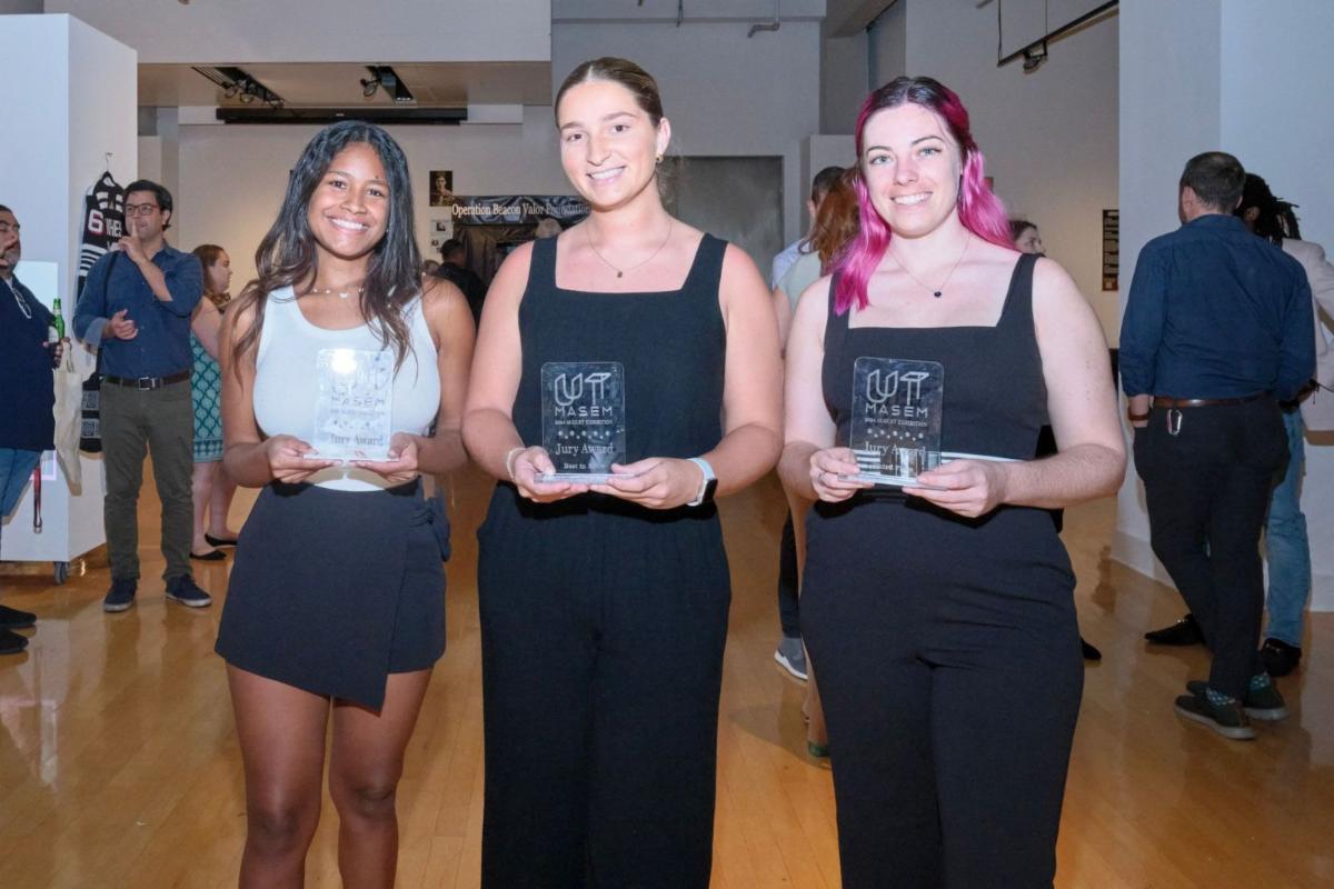 three female students standing and holding their awards