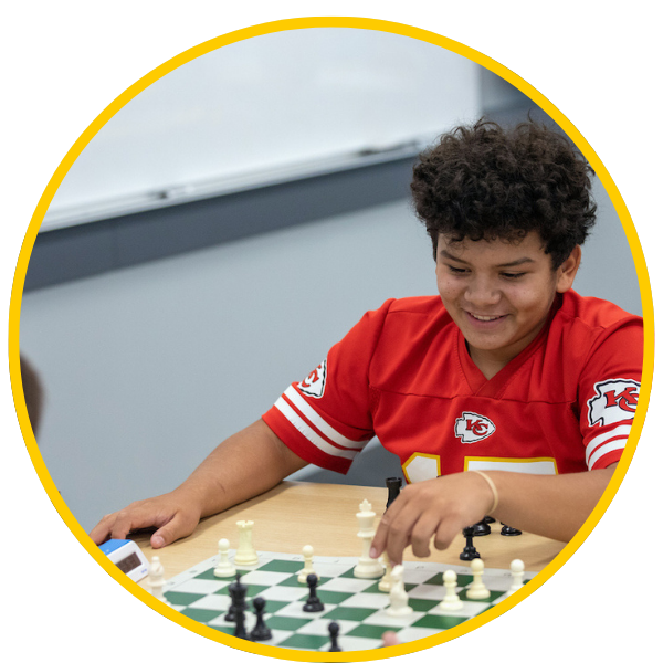 A young boy playing chess at a table.