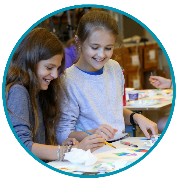 Two grade school girls working on art project water coloring.