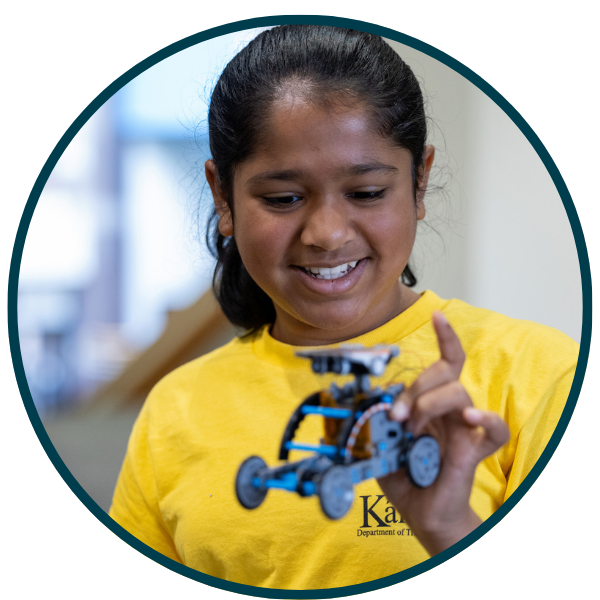 A young girl holding a motorized vehicle that she created in a STEM course.