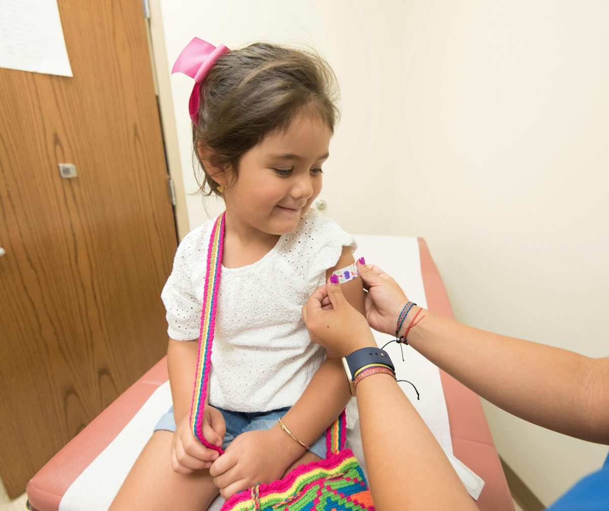 Young child with a bandage on her upper arm after receiving care