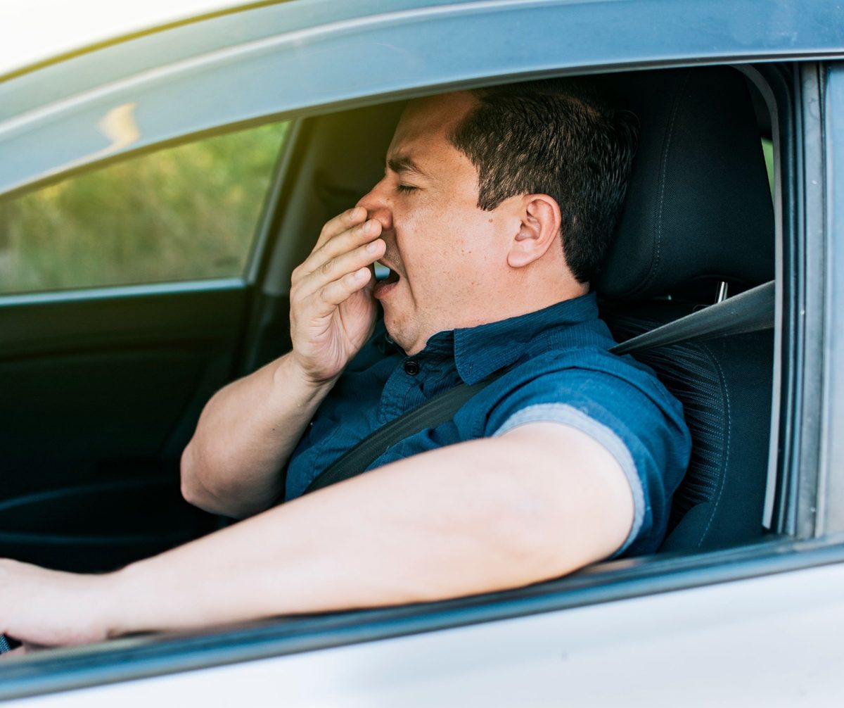 Tired adult yawning while seated in a car
