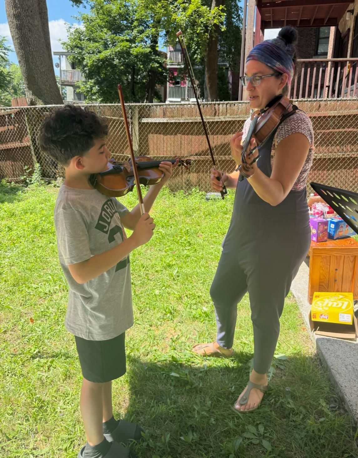 A musician and a child play violins during a Shelter Music Boston concert