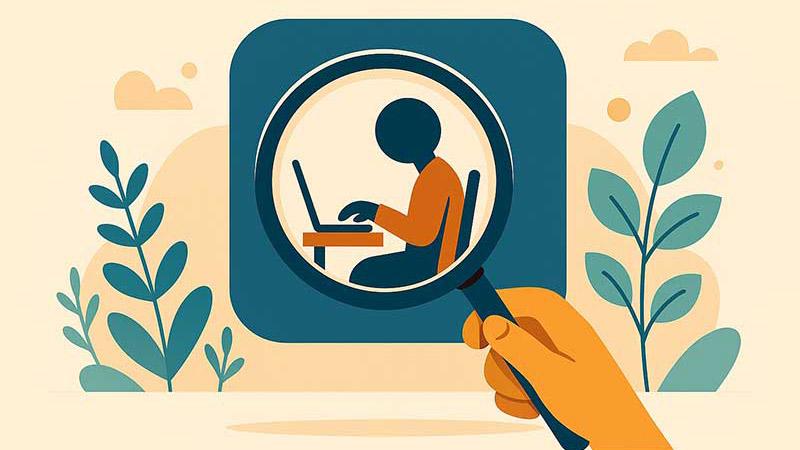 a student typing on a laptop is viewed through a magnifying glass