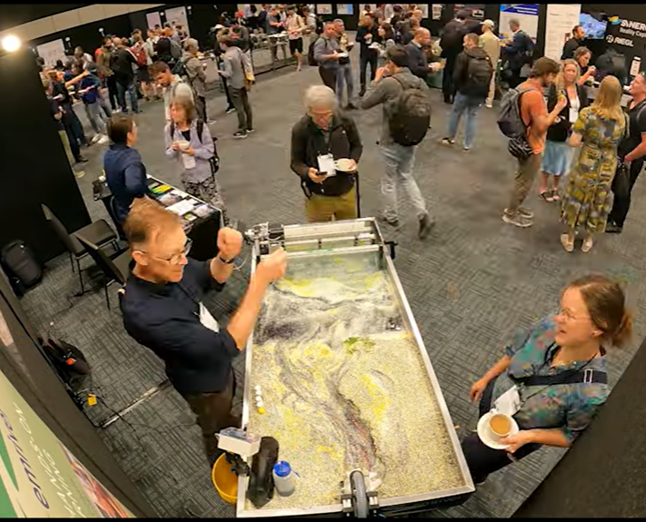 Photo of EmRiver Demonstration. A man is presenting about the stream table to an audience.