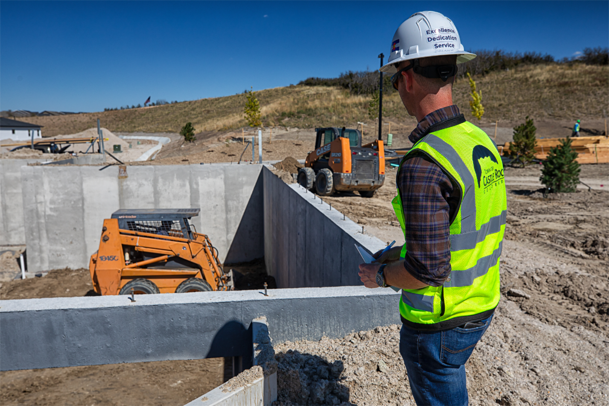 Town of Castle Rock employee in vest and hardhat inspects foundation of a new home under construction