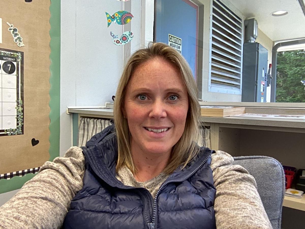 Person with long blond hair sitting in a chair and smiling 