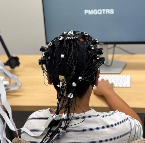 A child completes a task on the computer while hooked up to the brain imaging tool