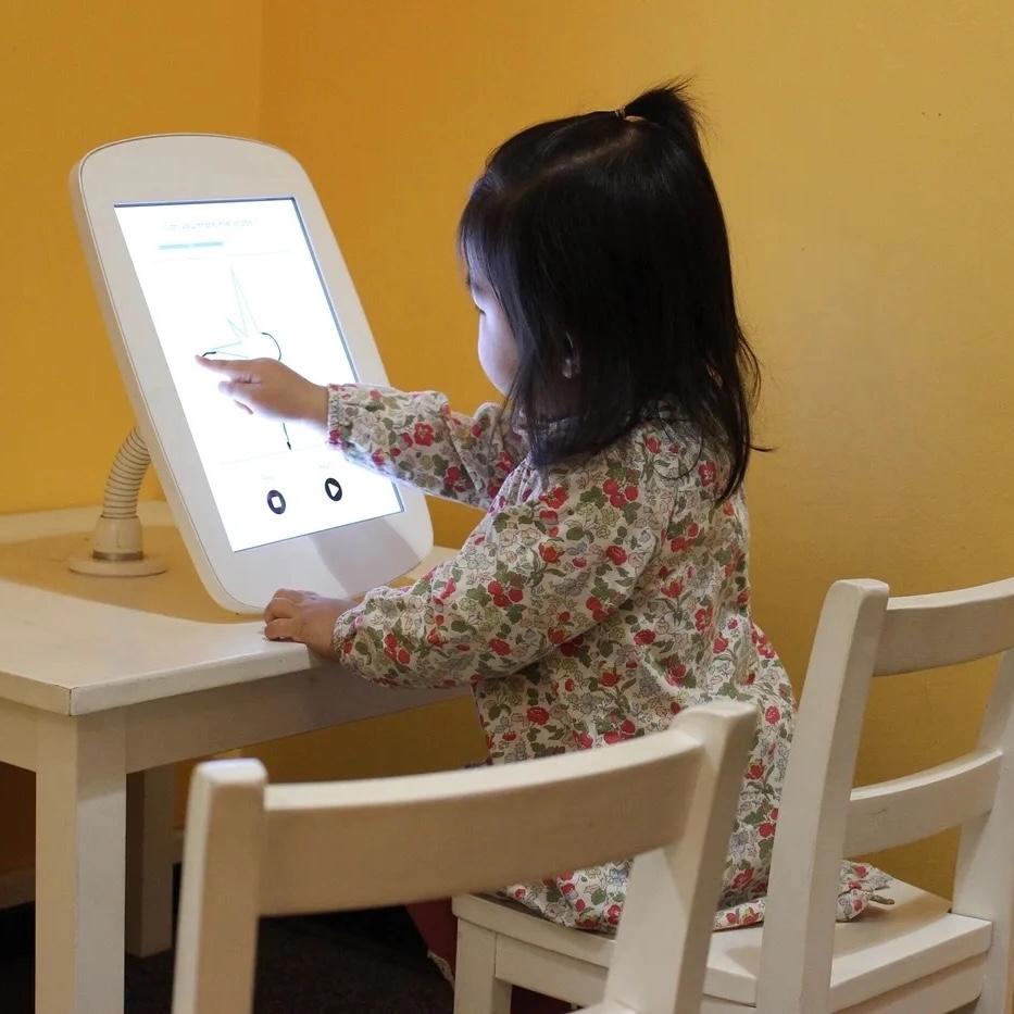 Child draws on an iPad at a table