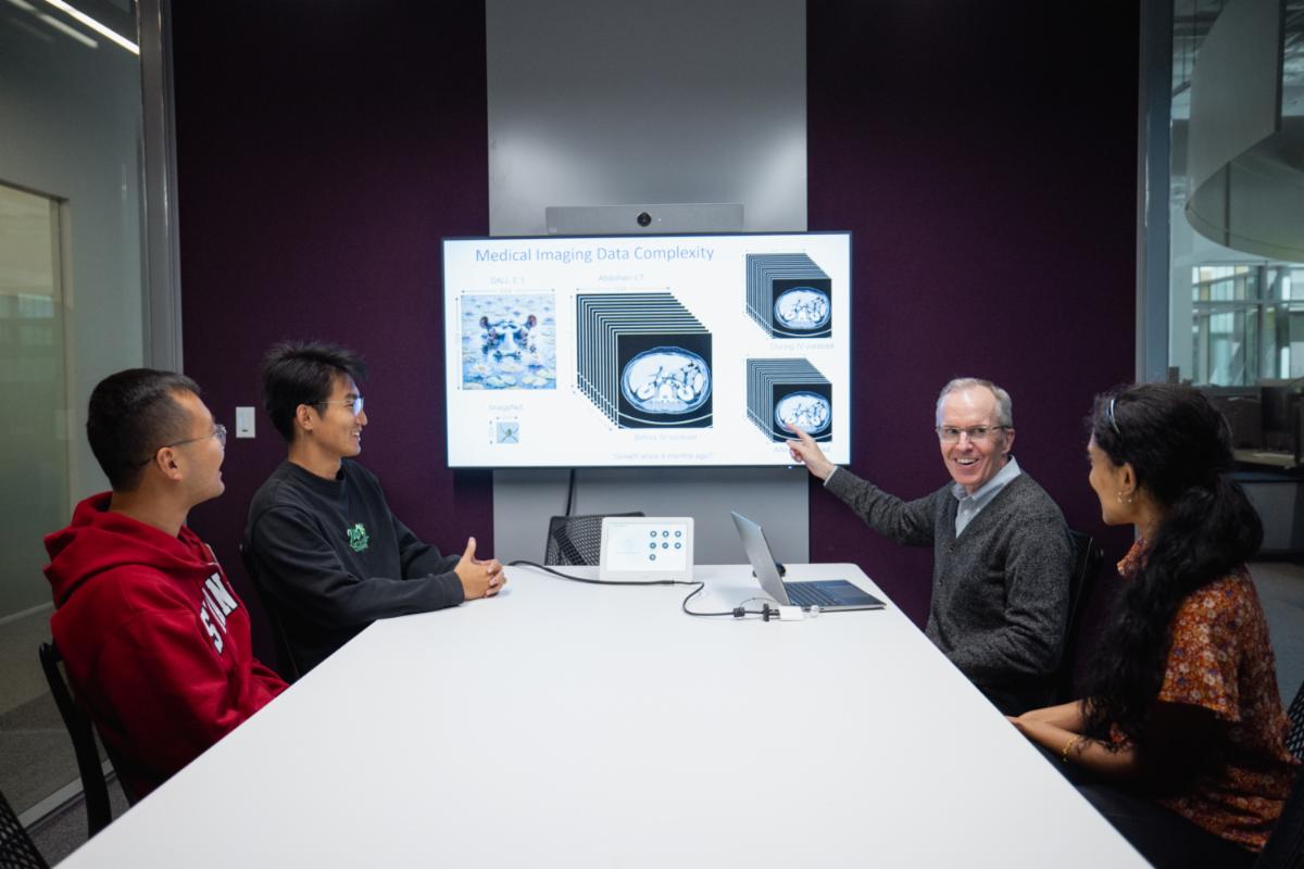 Curtis Langlotz and 3 colleagues sit around a table and review medical imaging data of a brain 