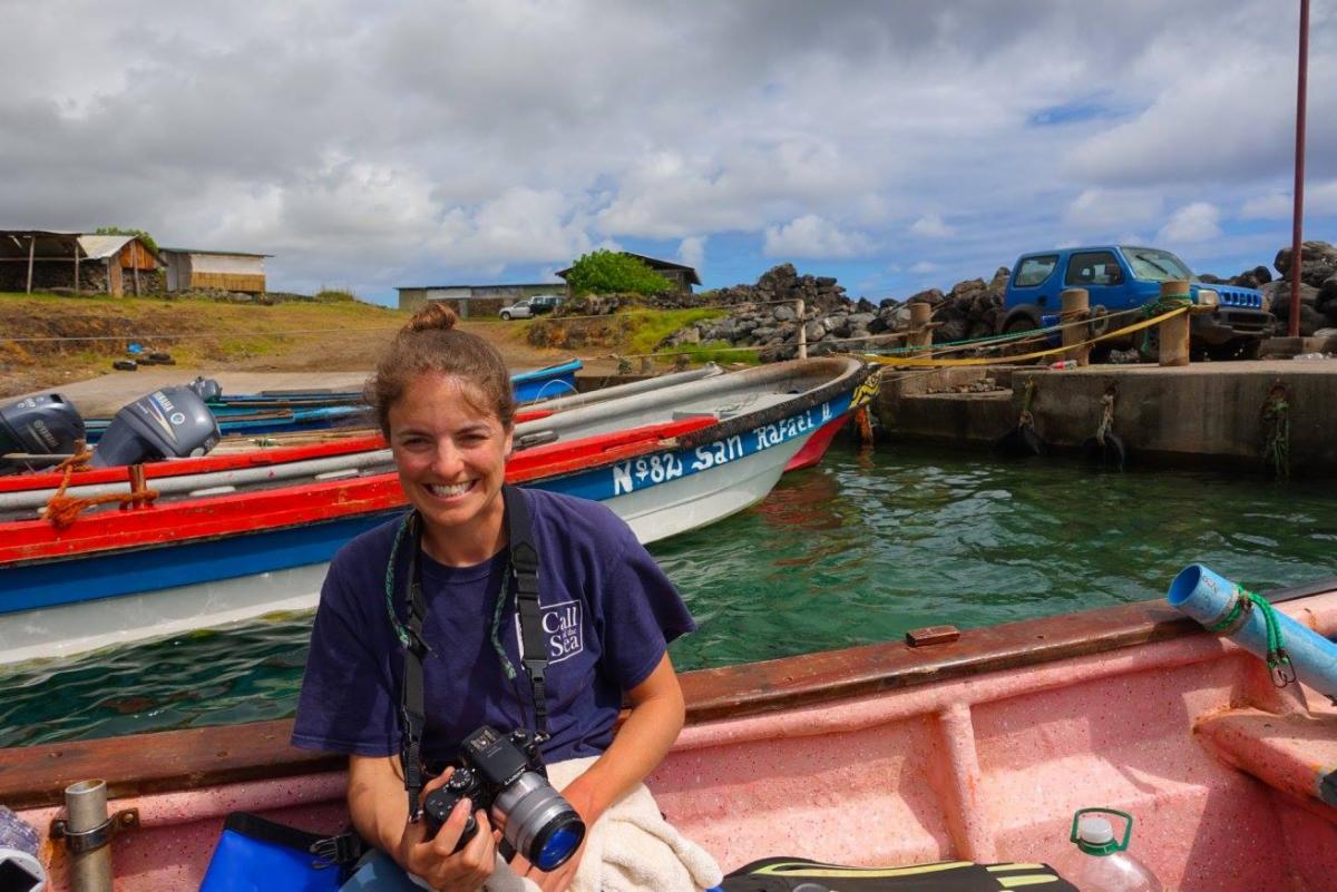 Katie smiles on a boat with a camera in her hands