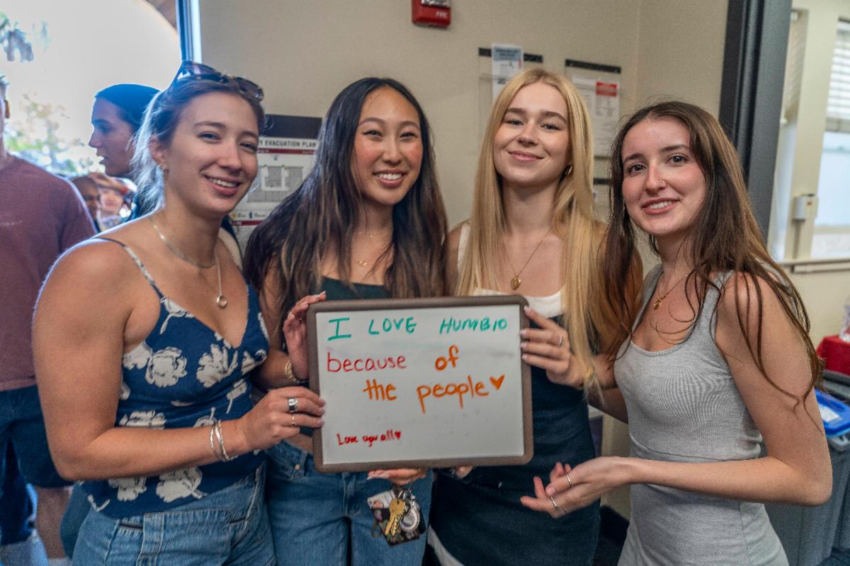 4 students smiling with a sign that says they love HumBio because of the people
