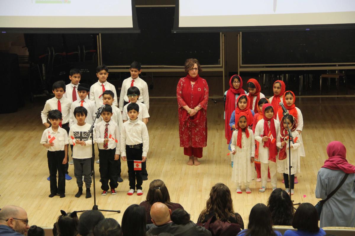 A person leads a group of children in cultural dress during a demonstration.